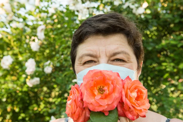 Picture of a middle-aged woman. Protection against coronavirus can also be beautiful. A woman has decorated the medical mask with roses.