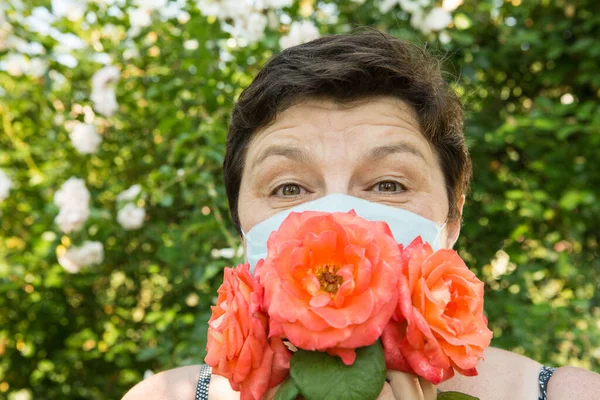 Picture of a middle-aged woman. Protection against coronavirus can also be beautiful. A woman has decorated the medical mask with roses.