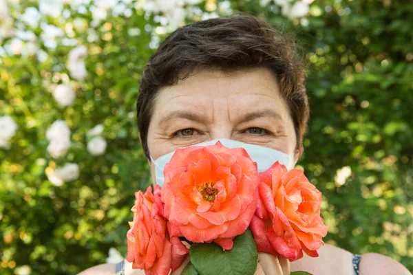 Picture of a middle-aged woman. Protection against coronavirus can also be beautiful. A woman has decorated the medical mask with roses.