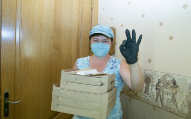 Teslimatçı kadın. Orta yaşlı bir kadın müşteriye pizza getirdi. Teslimatçının işi Coronavirus 'un koşullarında.
