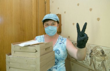 Teslimatçı kadın. Orta yaşlı bir kadın müşteriye pizza getirdi. Teslimatçının işi Coronavirus 'un koşullarında.