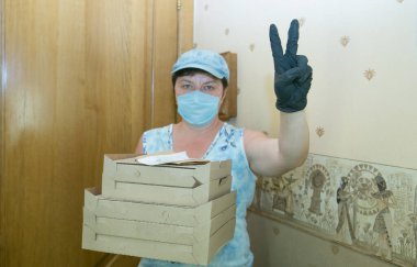 Bir salgının ortasında eve yiyecek teslimatı. Karton kutulardaki pizza bir teslimatçı kadın getirdi..