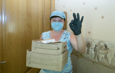 Bir salgının ortasında eve yiyecek teslimatı. Karton kutulardaki pizza bir teslimatçı kadın getirdi..