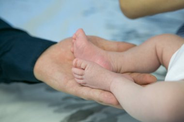 Çocuklar işte. Bebekler. Çocuk bakımı. Yeni doğmuş bir bebeğin küçük bacakları mutlu ebeveynlerin ellerinde.