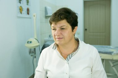 Hasta bir güzellik uzmanı. Orta yaşlı bir kadının portresi. Doktor hastaya yüz bakımına ihtiyacı olduğunu söyler..