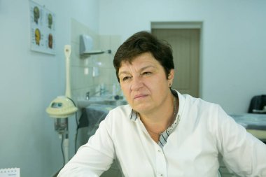 Hasta bir güzellik uzmanı. Orta yaşlı bir kadının portresi. Doktor hastaya yüz bakımına ihtiyacı olduğunu söyler..
