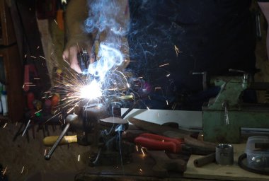 Aletle çalışmak. Kaynak makinesiyle çalışan genç bir adamın elleri. Kaynak kıvılcımları.