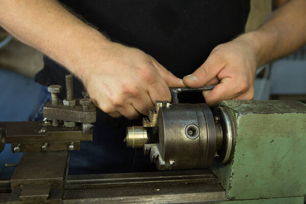 Работаю над токарным станком. Подготовка и настройка машины. Руки мастера.