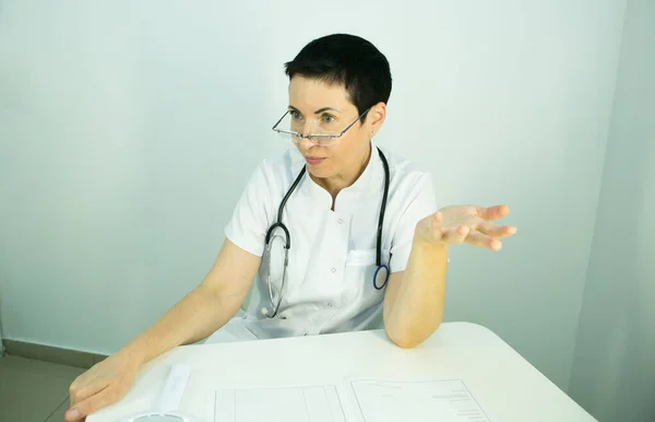 Doctor is a beautician. Portrait of a middle-aged woman. The doctor tells the patient about the need for facial skin care.