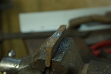 Mengene ve matkapla çalışıyor. Metal bir boşluk ile mengene.