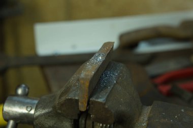 Mengene ve matkapla çalışıyor. Metal bir boşluk ile mengene.