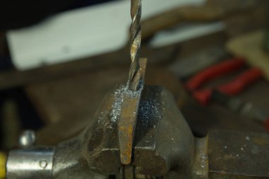 Mengene ve matkapla çalışıyor. Metal bir boşluk ile mengene.