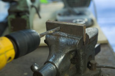 Mengene ve matkapla çalışıyor. Metal bir boşluk ile mengene.