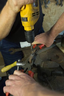 Mengene ve matkapla çalışıyor. Usta matkap kullanıyor. Bir ustanın portresi. Genç adam bir asistanla çalışıyor..