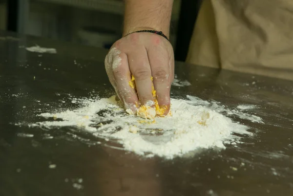 Healthy food concept. The process of making natural egg noodles. The chef\'s hands are kneading the dough.