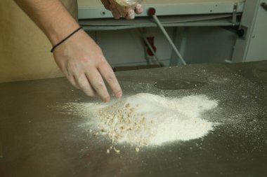 Ekmek yapma süreci. Şef hamuru elle yoğurur. Şefin elleri un ekliyor..