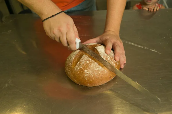 パンを作る過程 パンは準備ができている シェフは焼きたてのパンをキッチンナイフで切ります — ストック写真