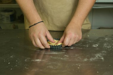 Meyveli tatlı hamur işleri için üretim süreci. Şef pişirme hamurunu elle yapar. Aşçı bitmiş hamuru kalıba koyar..