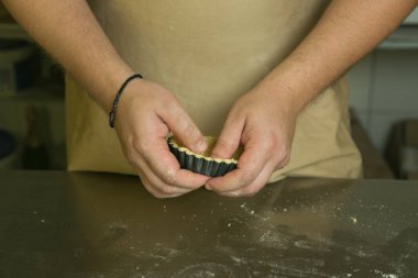 Meyveli tatlı hamur işleri için üretim süreci. Şef pişirme hamurunu elle yapar. Aşçı bitmiş hamuru kalıba koyar..