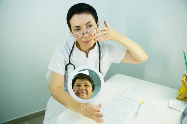 A visit to a beautician. The doctor tells the patient about the need for facial skin care.