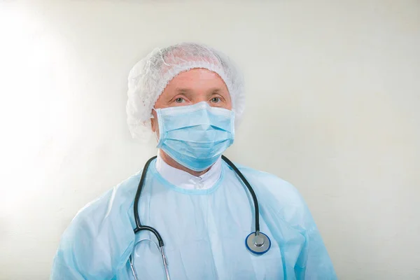 Portrait of a doctor man in a medical mask. There is a stethoscope on the doctor\'s neck. During a pandemic, remedies are essential. Isolated on white background.