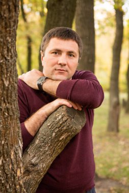 Orta yaşlı bir adam sonbahar ormanında dinleniyor. Portre.