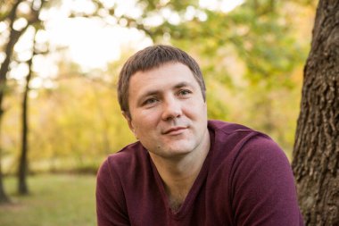 Orta yaşlı bir adam sonbahar ormanında dinleniyor. Portre.