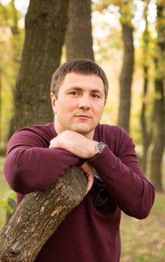 Orta yaşlı bir adam sonbahar ormanında dinleniyor. Portre.