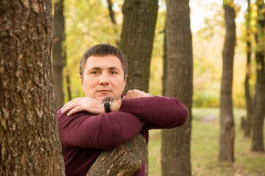 Orta yaşlı bir adam sonbahar ormanında dinleniyor. Portre.