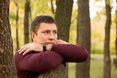 Orta yaşlı bir adam sonbahar ormanında dinleniyor. Portre.