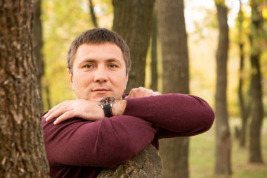 Orta yaşlı bir adam sonbahar ormanında dinleniyor. Portre.