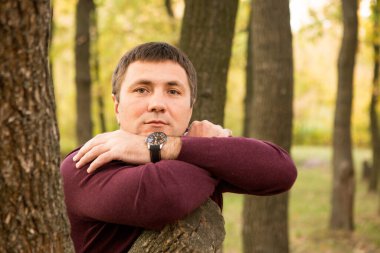 Orta yaşlı bir adam sonbahar ormanında dinleniyor. Portre.