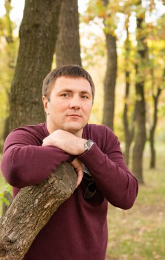 Orta yaşlı bir adam sonbahar ormanında dinleniyor. Portre.