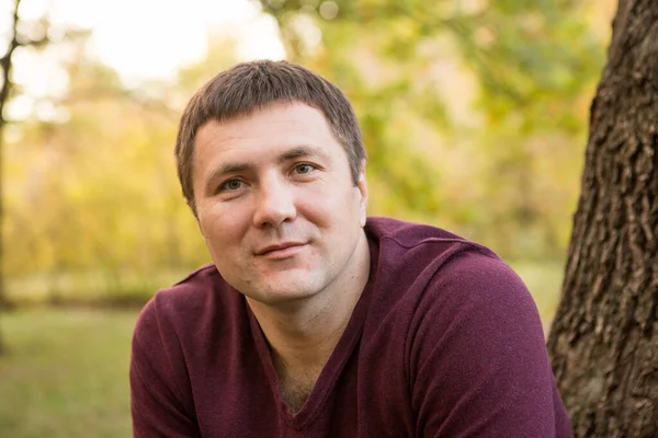 Orta yaşlı bir adam sonbahar ormanında dinleniyor. Portre.