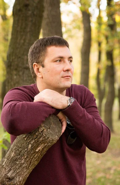 Orta yaşlı bir adam sonbahar ormanında dinleniyor. Portre.