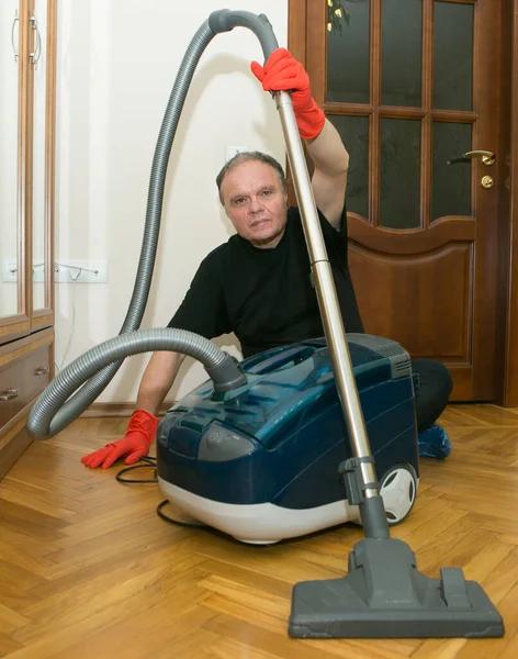 Emotions of a middle-aged man before cleaning an apartment. Daily cleaning of the premises. Humor. A man holds a vacuum cleaner in his hands.