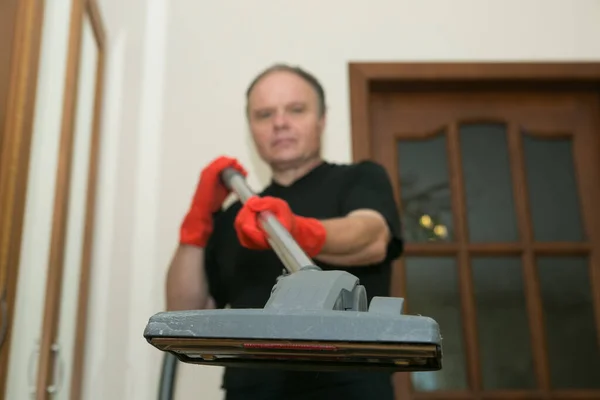 Emotions of a middle-aged man before cleaning an apartment. Daily cleaning of the premises. Humor. A man holds a vacuum cleaner in his hands.