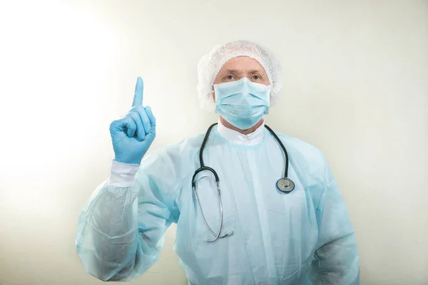 Portrait of a doctor in a medical mask and protective gloves. The doctor has a stethoscope around his neck. The doctor makes gestures with his hands.