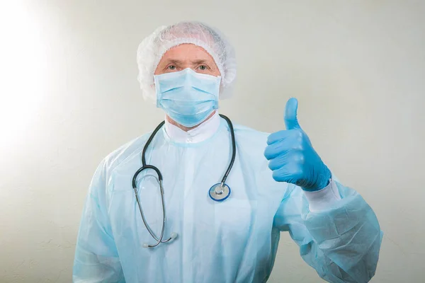 Portrait of a doctor in a medical mask and protective gloves. The doctor has a stethoscope around his neck. The doctor makes gestures with his hands.