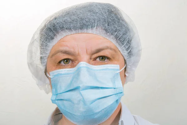 Surgical Nurse in cap and mask in medical clinic. Close-up portrait. Health care, surgery. Working in the face of the coronavirus pandemic.
