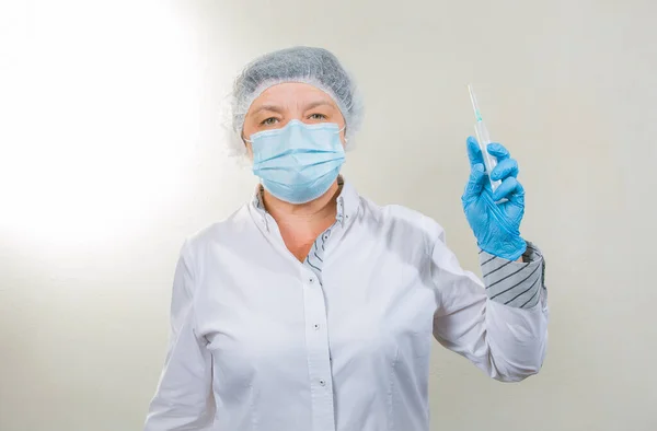 Surgical Nurse in cap and mask in medical clinic. A syringe with medicine is in the hands of a nurse. Close-up portrait. Health care, surgery.