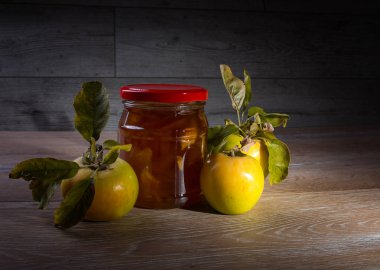 Durgun hayat. Meyve reçelini ve eski ahşap bir masanın üzerindeki taze sarı elmaları kapat. Sonbahar hasadı hala yaşam konsepti.