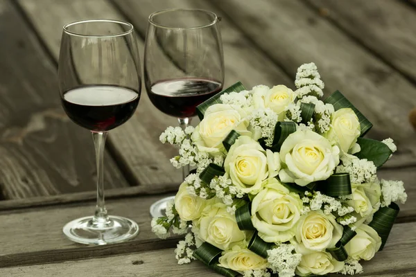 Wedding bouquet. Glasses with red wine and a wedding bouquet on the background of old wooden boards. The most important bouquet at the wedding is the bride\'s bouquet.