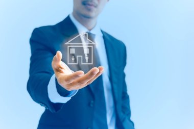Kadın ve erkek simgesi olan bir ev mavi arka planda tutan kavramsal işadamı el