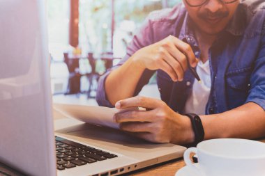 Anlaşma formu, laptop ve kahve tablo üzerinde kalem tutan işadamı el