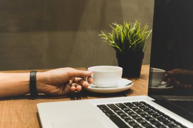 Kahve fincanı ile lapyop ahşap masa üzerinde mat renkte tutan Slected odak el