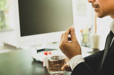 Çalışma masası bardak su sağlık için ofiste, hap alarak iş adamı