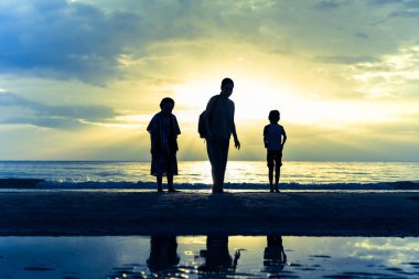 Tropik ada günbatımı sırasında sahilde rahatlatıcı aile.