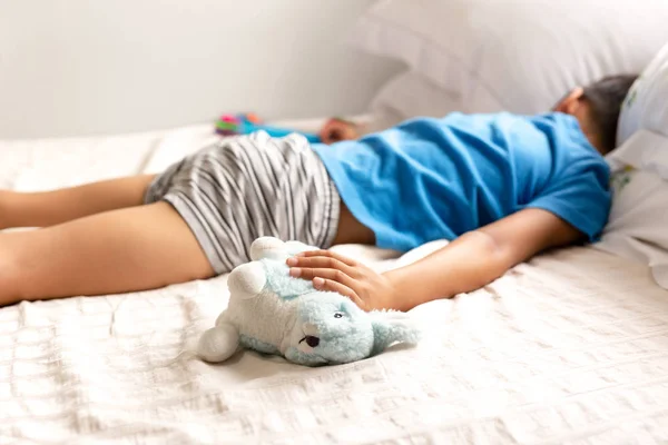 Маленький мальчик спит в постели и держит своего кролика . — стоковое фото