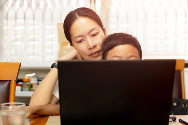 母亲和儿子坐在餐桌上在家里和使用笔记本电脑在早上. — 图库照片